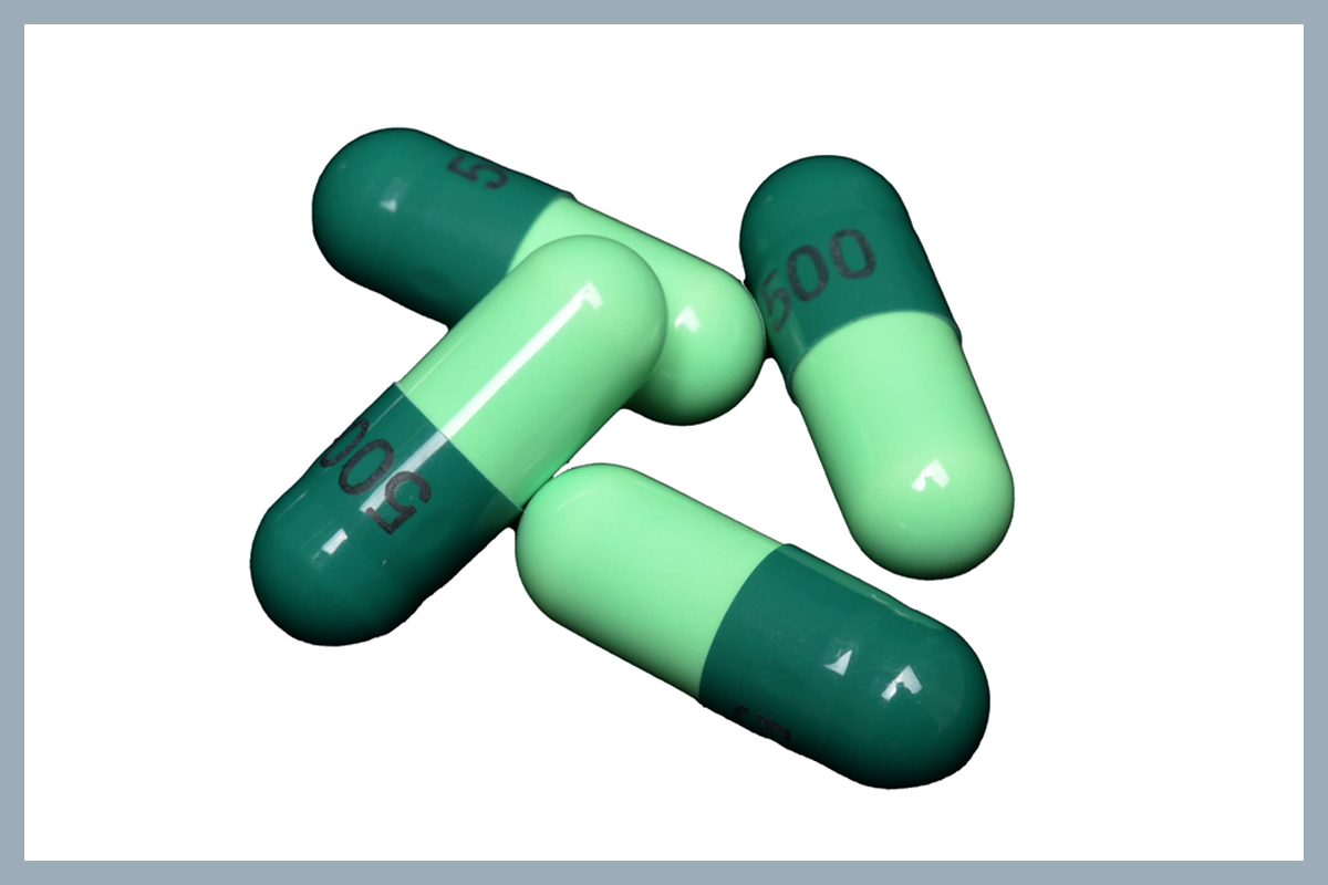 Four green medicine capsules, with darker green on one half and lighter green on the other