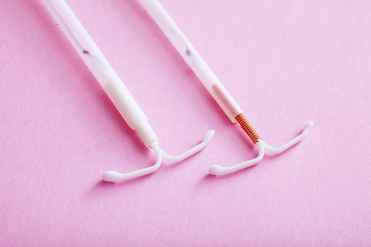 Photo of Hormonal and Copper IUDs on pink background Photo of Hormonal and Copper IUDs on pink background