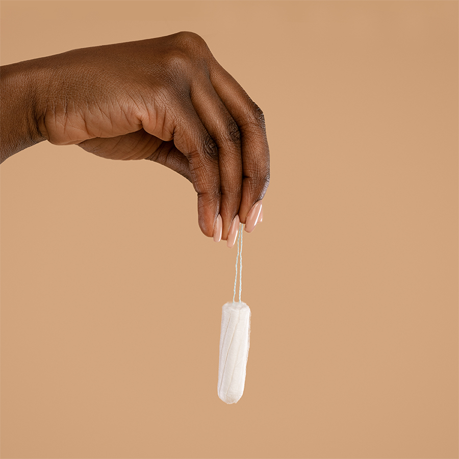 Hand holding tampon on brown background